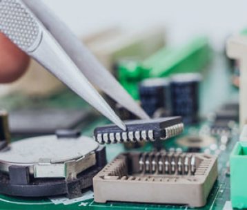 A technician removing a chip from a printed circuit board using a pair of pliers