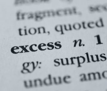 Close up of the word excess as defined in a dictionary